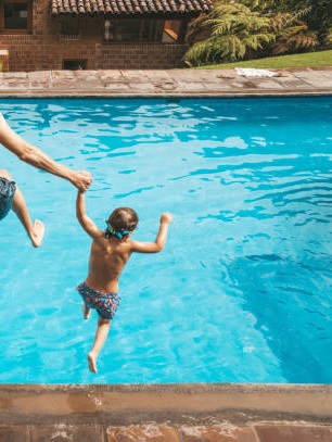 photo droite d'un papa et son fils qui sautent dans une piscine